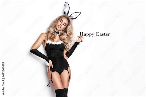 Sexy Blonde Model Dressed In Easter Bunny Costume And Bunny Ears Is Standing On A White