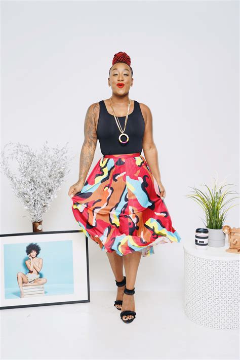 A woman with a colourful dress posing next to a picture frame and
