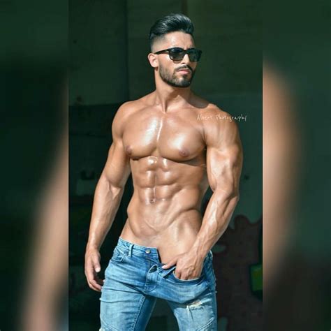 A Shirtless Man In Jeans And Sunglasses Posing For The Camera With His