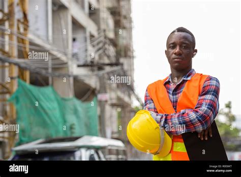 Young Black African Man Construction Worker Holding Clipboard An Stock