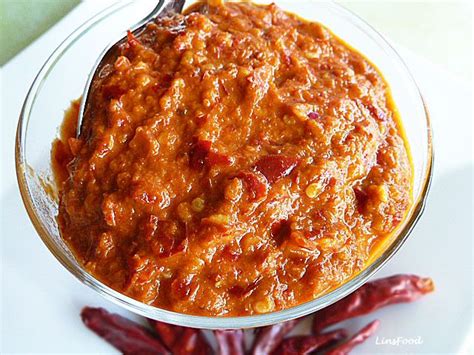 A Bowl Filled With Chili Sauce Next To Some Red Chilli Peppers On A