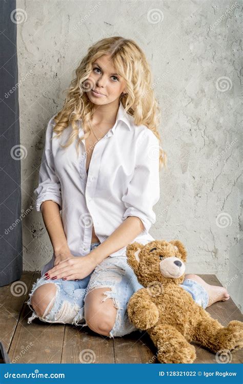 Jeune Belle Blonde De Fille Dans Une Chemise Blanche Et Des Jeans Avec Des Lacunes Photo Stock