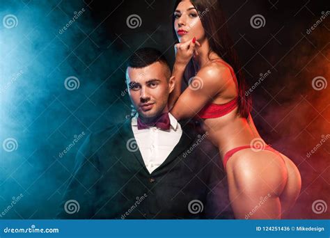 Portrait Of And Fit Woman Wear Red Lingerie And Hugging Handsome Fitness Man In Black Suit Stock