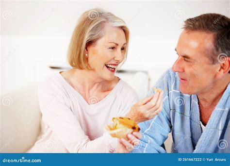 Cheerful Mature Woman Feeding Muffin To Her Husband Portrait Of A Cheerful Mature Woman Feeding