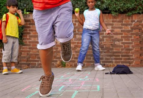 Criança Pulando Amarelinha - Crianças multiétnicas brincando de amarelinha e pulando no playground ...