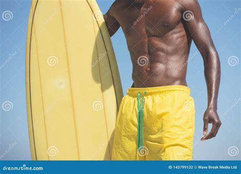 Male Surfer With A Surfboard Standing On A Beach Stock Photo Image Of