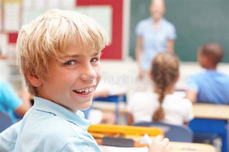 He Loves School Portrait Of A Cute Blonde Boy In Sitting At A Desk In Class Stock Photo