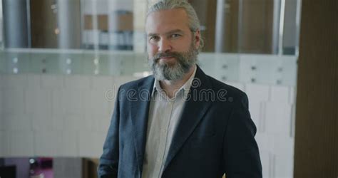 Portrait Of Ambitious Mature Entrepreneur Smiling And Looking At Camera Indoors In Hotel Lobby