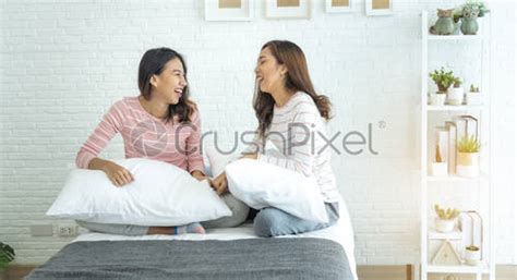 Two Asian Lesbian Women Looking Together In Bedroom Couple People