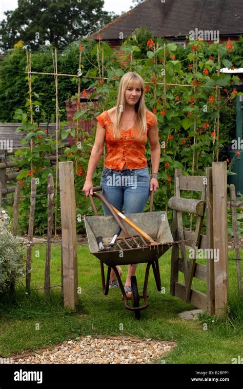 Woman Pushing Wheelbarrow In Country Garden Southern England Uk Stock