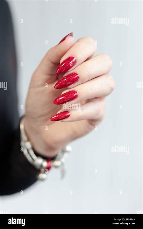 Womans Hands With Long Nails And A Bottle Of Red Nail Polish Stock