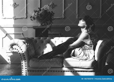 Belle Jeune Femme Blonde Sexy Dans Une Robe Longue En Soie Se Reposant Sur Un Divan Treignant