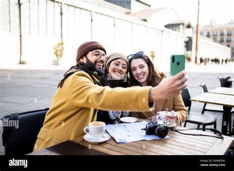 Group Of Three Happy Friends Taking Selfie In Outdoor Cafe On Sunny Day