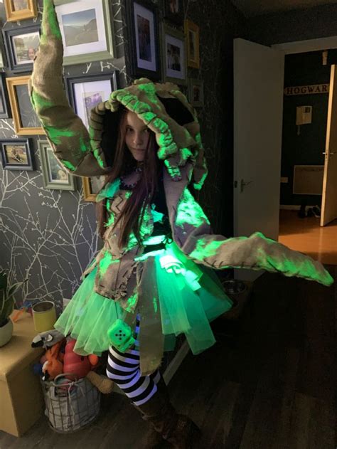 A Woman Dressed Up As A Witch With Green Lights On Her Hands And Legs