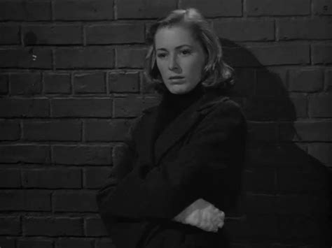 A Woman Standing In Front Of A Brick Wall With Her Arms Crossed And