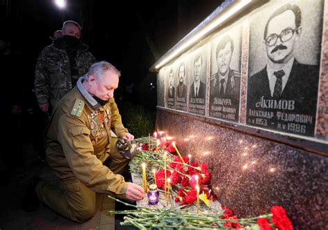 A man lights a candle at a memorial, dedicated to firefighters and workers who died after the ...