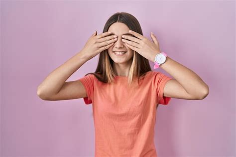 Adolescente Debout Sur Fond Rose Couvrant Les Yeux Avec Les Mains