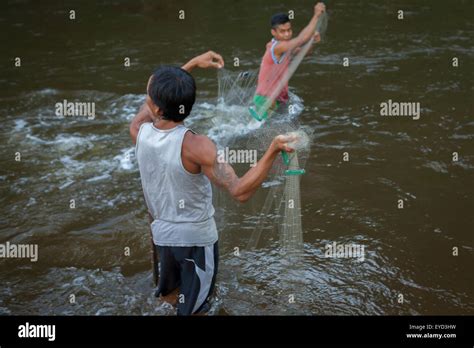 Men Using A Fishing Net On A River Near The Longhouse Of Traditional