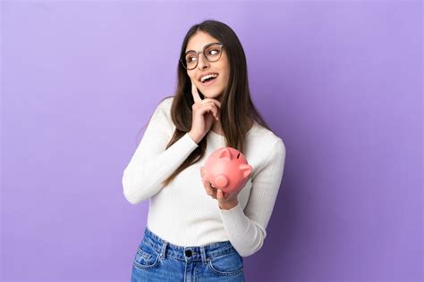 Jovem Mulher Caucasiana Segurando Um Cofrinho Isolado No Fundo Roxo