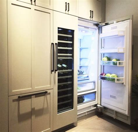 An Open Refrigerator In A Kitchen With White Cupboards And Drawers On