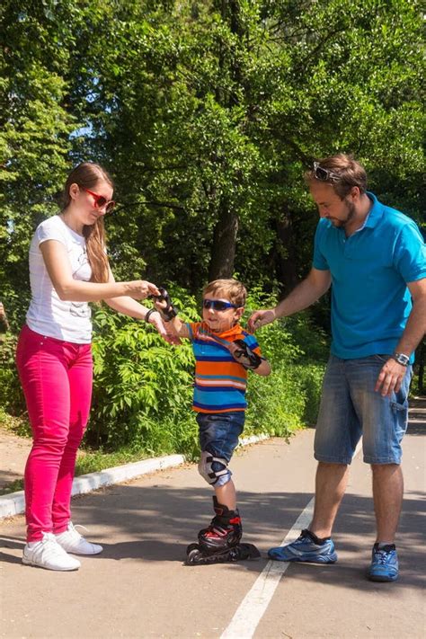 Os Pais Ensinam O Filho Pequeno Montar Em Patins De Rolo Imagem De