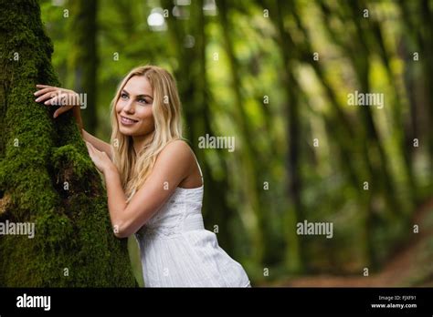 Beautiful Blonde Woman Standing Next To A Tree Trunk Stock Photo Alamy