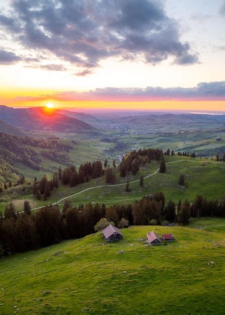 Uma fazenda no alto das colinas durante um pôr do sol ao longe você