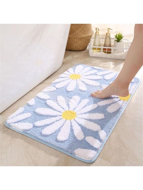 a person standing on a bath mat with white and yellow daisies in the center