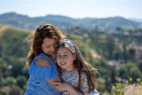 Madre E Hija De Latina Que Sonr En Y Que R En En Una Colina Delante De Las Flores Amarillas