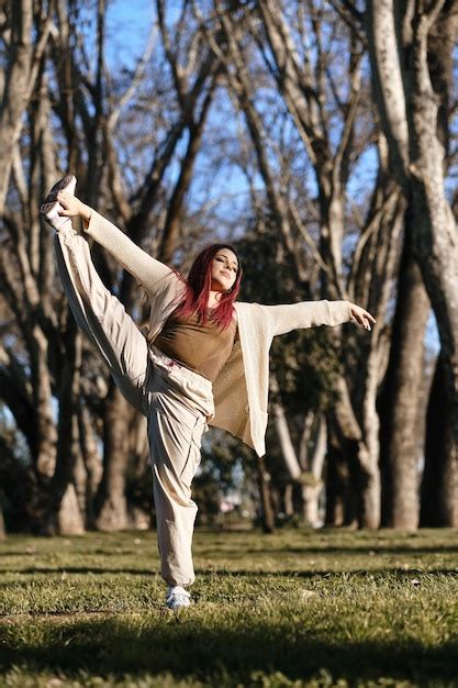 Foto Vertical De Una Joven Latina Abriendo Las Manos Y Levantando Un Pie En Pose De Baile Foto