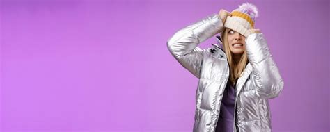 Inconfortable embarrassé jolie fille blonde inquiète tirant le chapeau visage se cachant de son