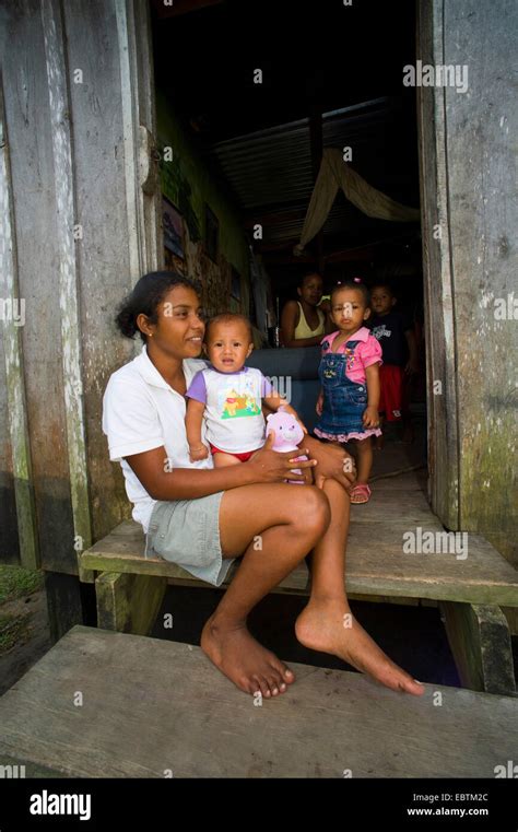 Indian Native Woman With A Baby Sitting On The Doorstep Of Her Wooden