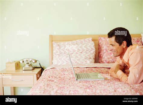 Side Profile Of A Mature Man Lying On The Bed In Front Of A Laptop And Smiling Stock Photo Alamy
