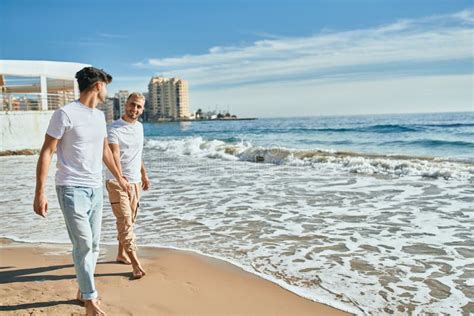 Jovem Casal Gay Sorrindo Feliz Caminhando Na Praia Imagem De Stock