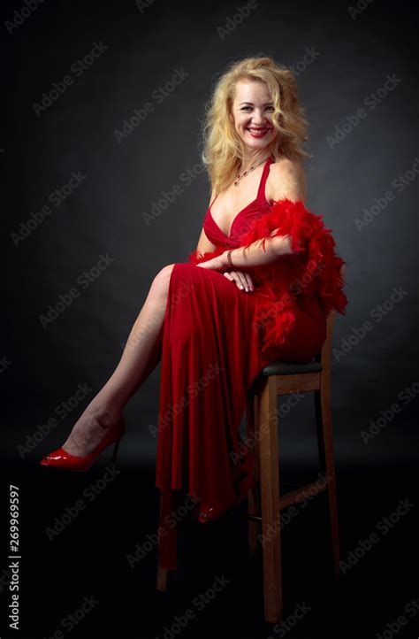 Attractive Smiling Mature Woman In Red Evening Dress With Fluffy Feather Boa Stock Photo