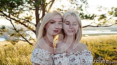 Two Cute Blonde Girlfriends In Identical Dresses Posing For The Camera On The Field Stock