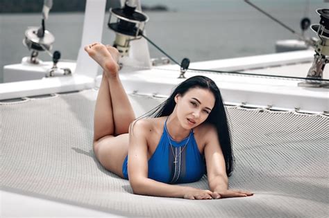 Schöne junge Frau im blauen engen Bikini entspannt sich auf dem Netz der privaten Yacht im Meer