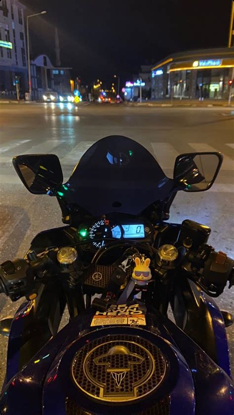 The Motorcycle Is Parked On The Side Of The Road In The City At Night Time