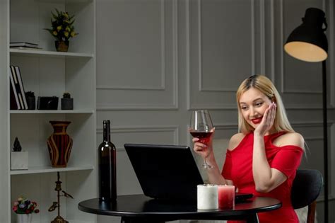 Amour virtuel jolie fille blonde en robe rouge à distance avec du vin tenant les mains sur le