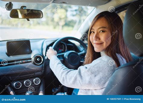 A Woman Holding Steering Wheel While Driving A Car On The Road Stock