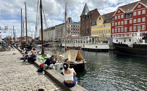 Visitors On Nyhavn Copenhagen Harbor With Classic Boats And Houses