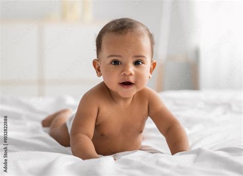 Portrait Of Cute Small African American Baby Crawling On Bed On The White Blanket At Home Naked