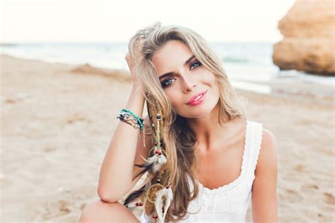 Closeup Portrait De Jolie Fille Blonde Aux Cheveux Longs Et Aux Yeux Bleus Assis Sur La Plage