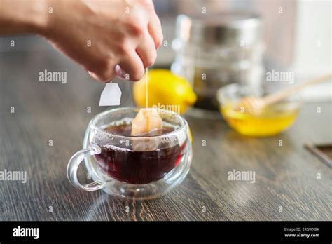 Womans Hand Puts The Tea Bag In The Glass Cup With Hot Water Stock