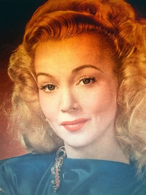 An Old Photo Of A Woman With Blonde Hair And Blue Dress Looking At The