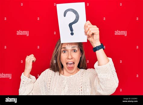 Jeune belle femme blonde tenant la marque d interrogation sur la tête pointant le pouce jusqu au