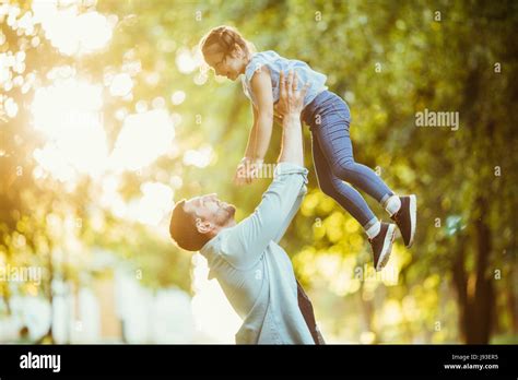 Father And Daughter Are Playing And Hugging Outdoors In Summer Park On