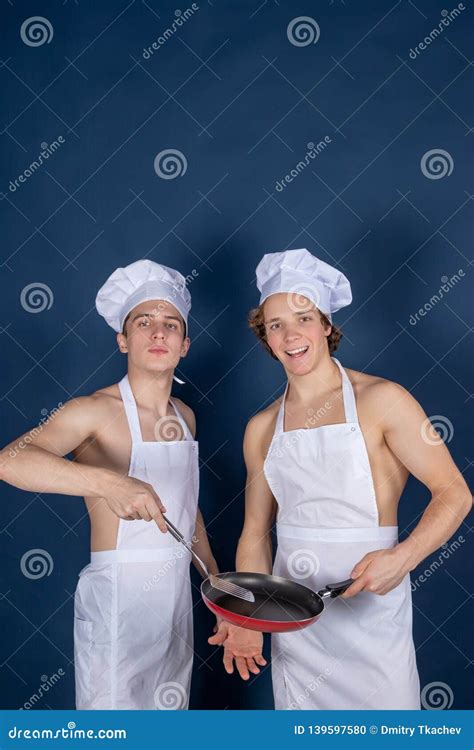 Two Handsome Chefs With Apron On Naked Muscular Body With Kitchen Utensils On Blue Background