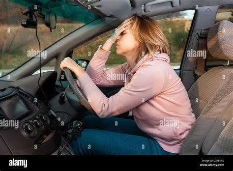 Portrait d une jeune femme blonde stressée est assise derrière le volant d une voiture à droite