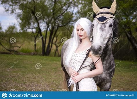Une Femme Blonde Sexy Et Sexy Du Caucase Avec De Longs Cheveux Blancs Debout Avec Un Cheval